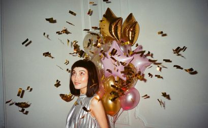 Female model standing in front of a bunch of metallic helium balloons